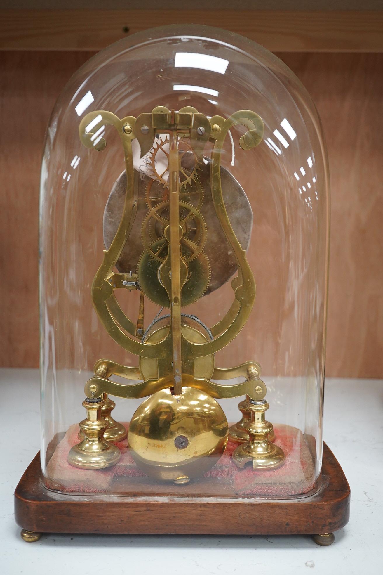 A late 19th century brass skeleton timepiece, the silvered chapter ring with Roman numerals, on a stand, under a glass dome, 37cm high. Condition - pendulum adjustment needed